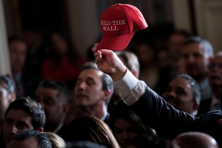 Fredy Burgos, of Virginia, holds up a 'Build the Wall' hat while waiting with others for a Hispanic Heritage Month event in the East Room of the White House